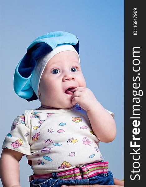 Amusing baby boy in a beret in a studio on a dark blue background