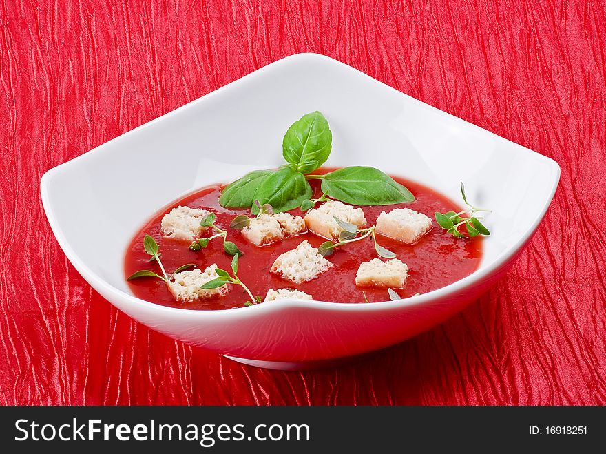 Bowl of tomato soup over red background