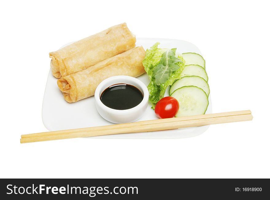 Chinese pancake rolls on a plate with soy sauce dip; and a salad garnish; chopsticks on the edge of the plate