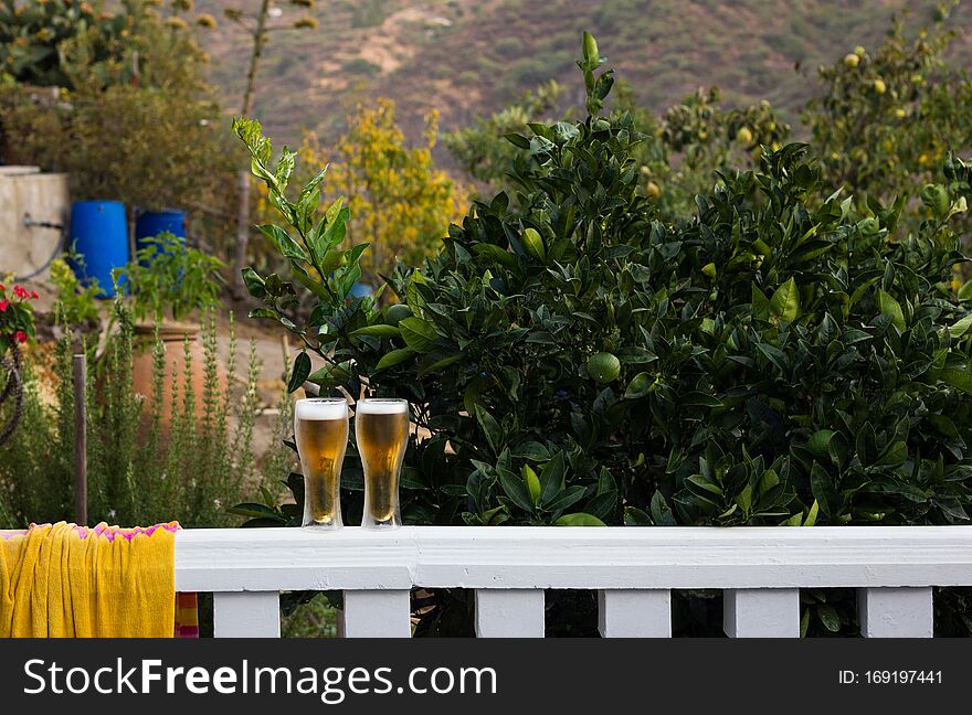 Two pints of beer on terrace white railing. Alcoholic drinks on nature outdoors. Party, celebration concepts