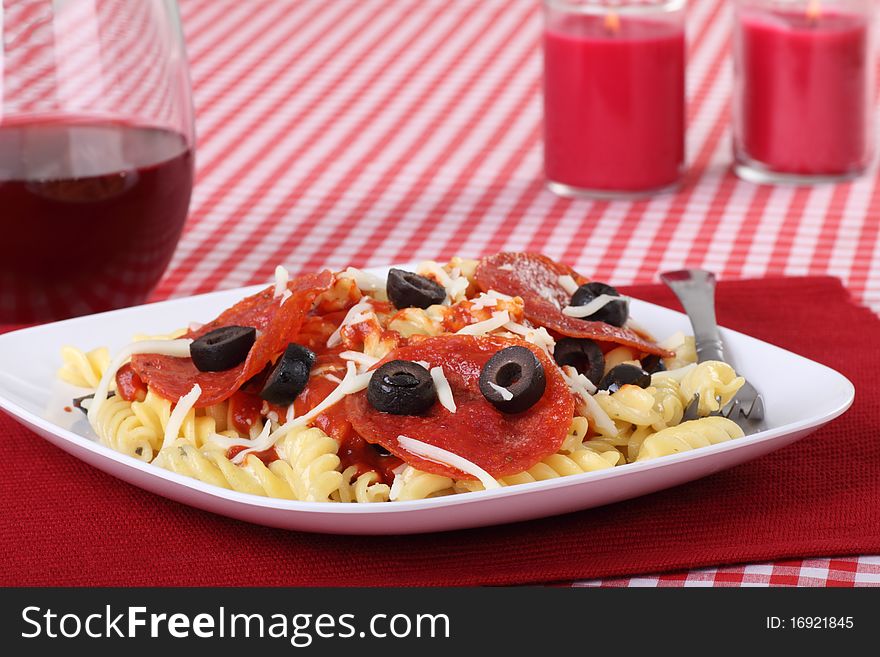 Pepperoni pasta meal topped with black olive slices and cheese