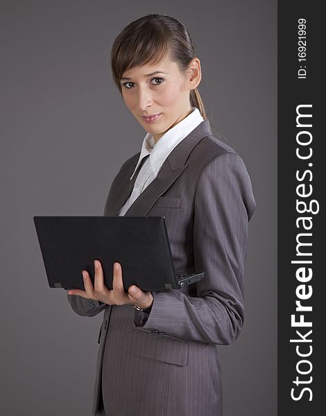 Portrait of businesswoman with small laptop over grey background. Portrait of businesswoman with small laptop over grey background