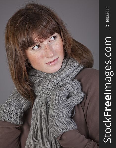 Portrait of woman in wool scarf over grey background. Portrait of woman in wool scarf over grey background