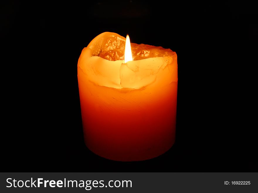 Yellow candle burning on a black background