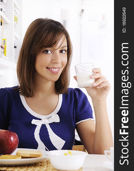 Young woman drinking milk on the white background, smiling and looking in camera