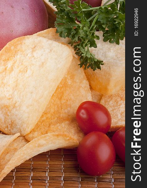 Potato chips with a potato on a wooden tray.