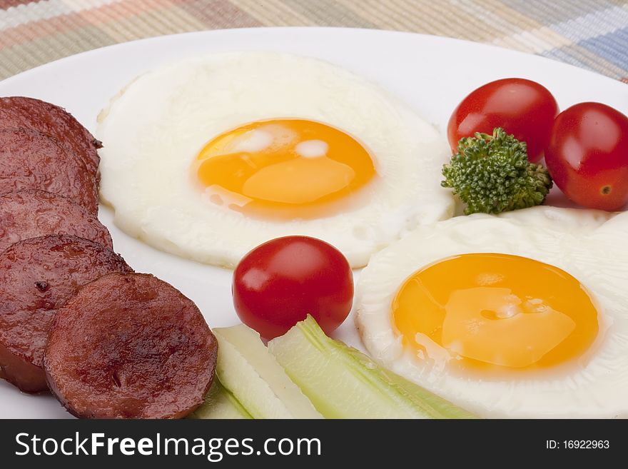 Fried eggs with fried sausage and vegetables.