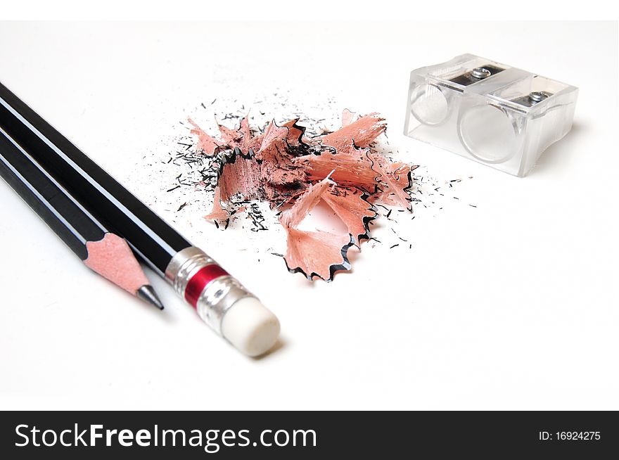 Two black pencils with sharpener and shavings over white background. Two black pencils with sharpener and shavings over white background