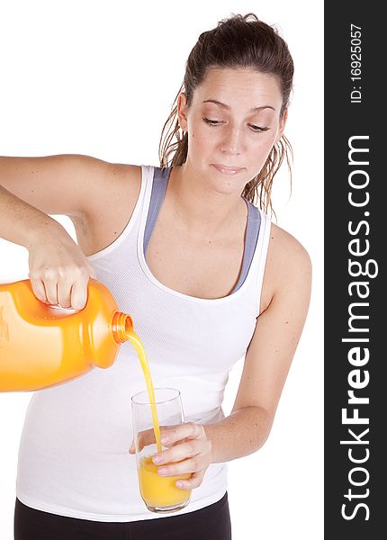 A woman in fitness attire is pouring a glass of orange juice. A woman in fitness attire is pouring a glass of orange juice.