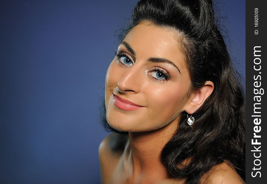 Beauty portrait of pretty casual woman with pure skin and natural make-up holding her black curly hair up and smiling