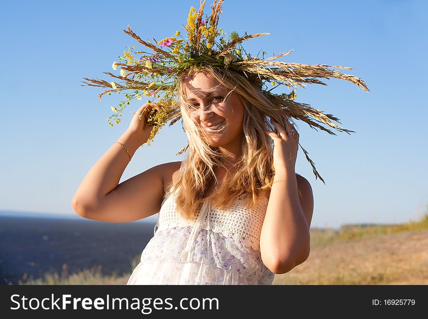 The girl in a wreath from the wild flowers, smiling and happy