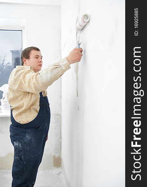 Student worker painting white wall with roller. Student worker painting white wall with roller