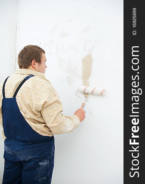 Worker painting white wall with roller. Home improvement concept. Worker painting white wall with roller. Home improvement concept