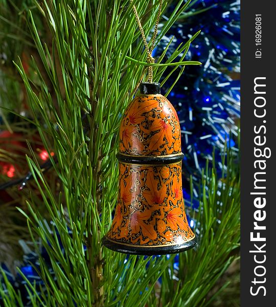 Painted wooden bell and tinsel on Christmas-tree. Painted wooden bell and tinsel on Christmas-tree