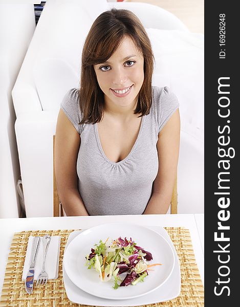 Young woman eating salad on white background