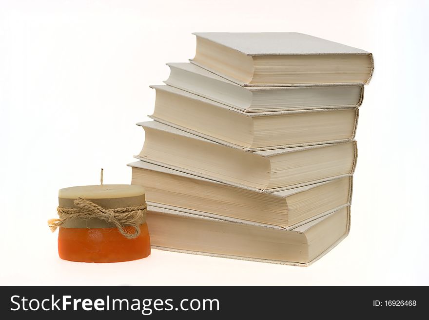 Books are stacked with candles on a white background