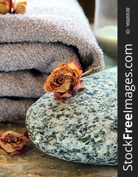 Gray towel with a rock and a candle and dry roses