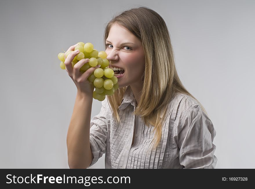 Beautiful young woman eating grapes