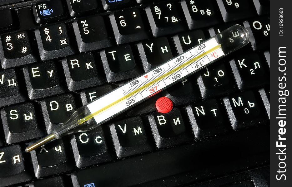 Mercury thermometer lying on computer keyboard. Mercury thermometer lying on computer keyboard