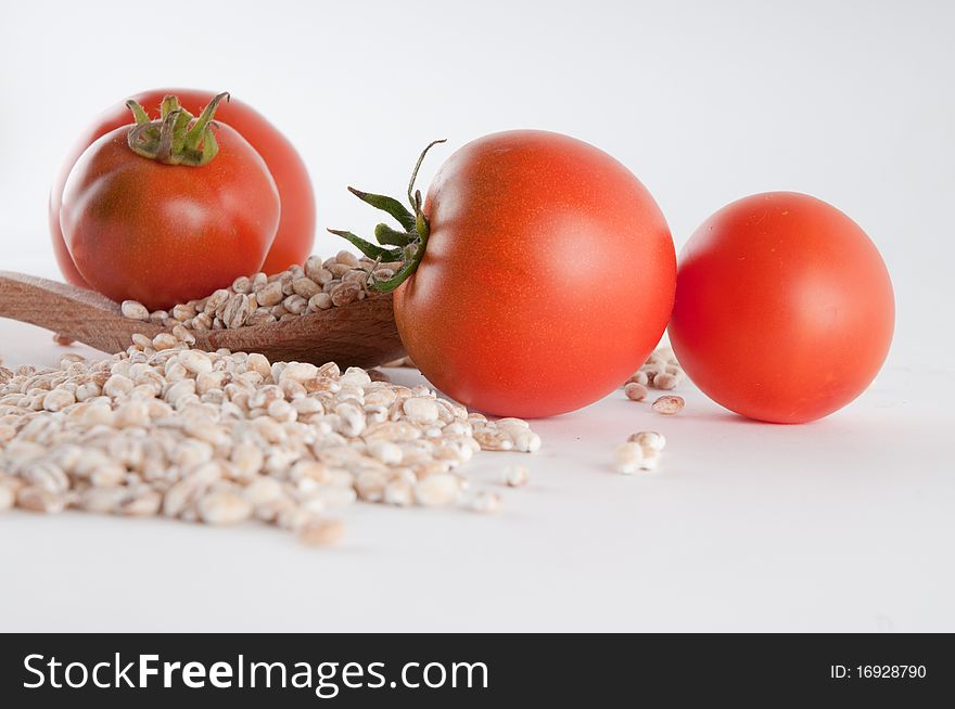 Grain and tomatoes spilled over a wooden spoon