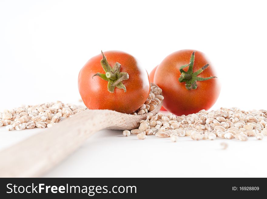 Grain and tomatoes spilled over a wooden spoon