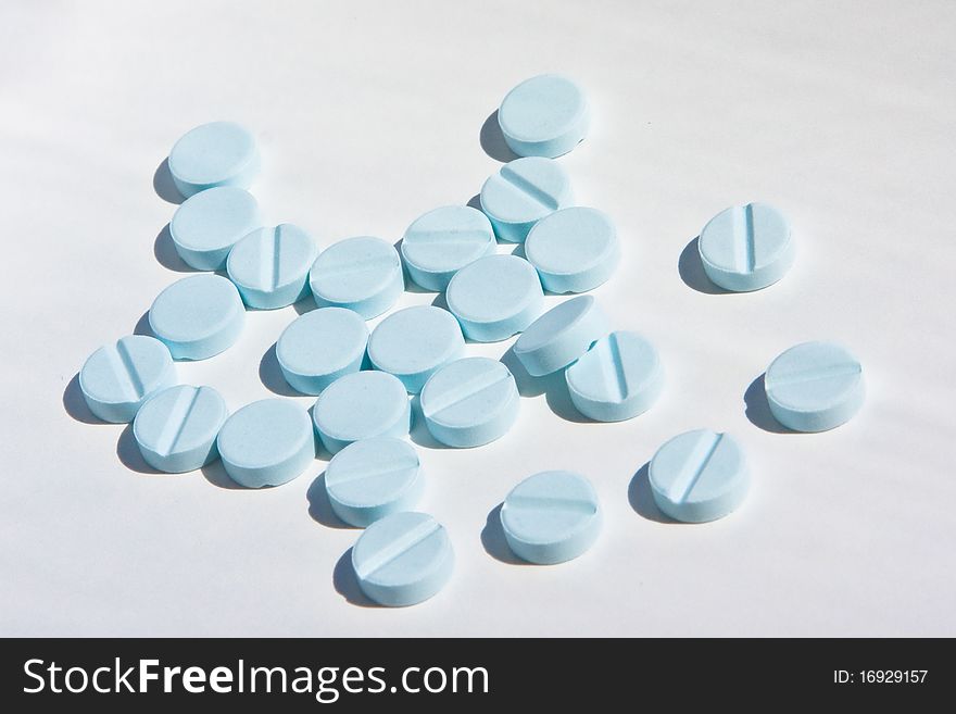 Some small blue  pills on white background. Some small blue  pills on white background