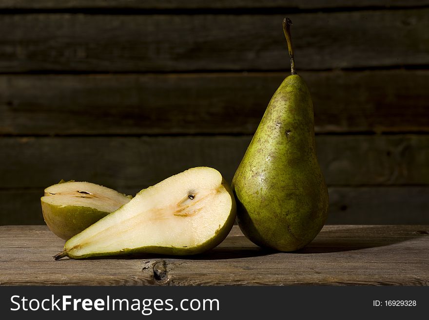 Belgian pear lying on a wooden table. One pear cut. Belgian pear lying on a wooden table. One pear cut.