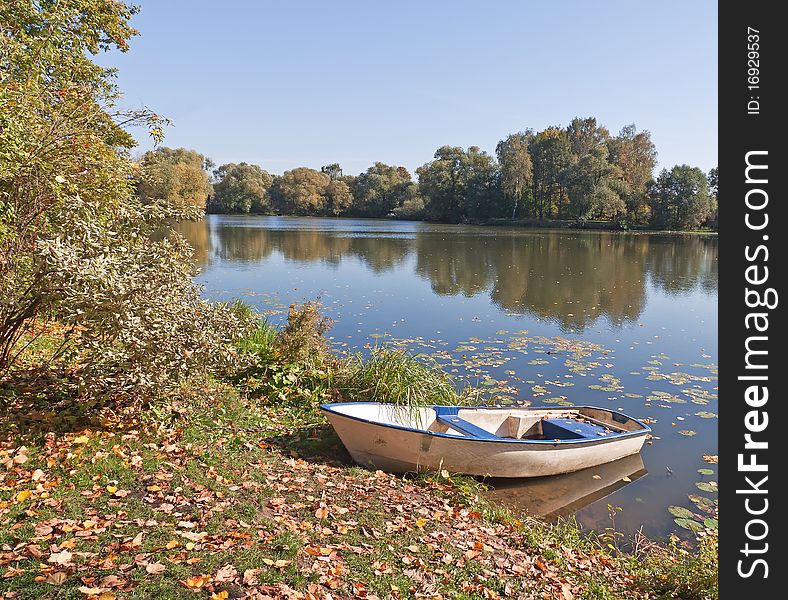 Boat on pond bank in park. Autumn season