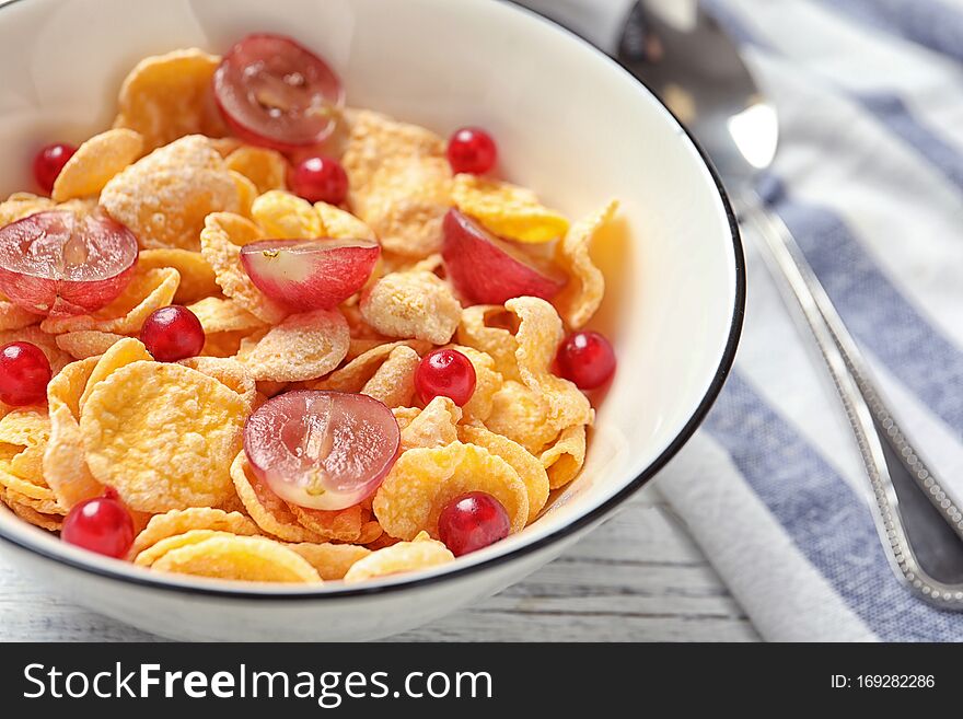 Corn flakes with berries on table, closeup. Healthy breakfast