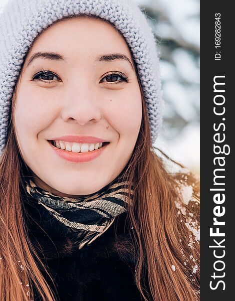Close-up winter portrait of a beautiful smiling woman and looking at the camera. Human positive emotions concepts. Close-up winter portrait of a beautiful smiling woman and looking at the camera. Human positive emotions concepts