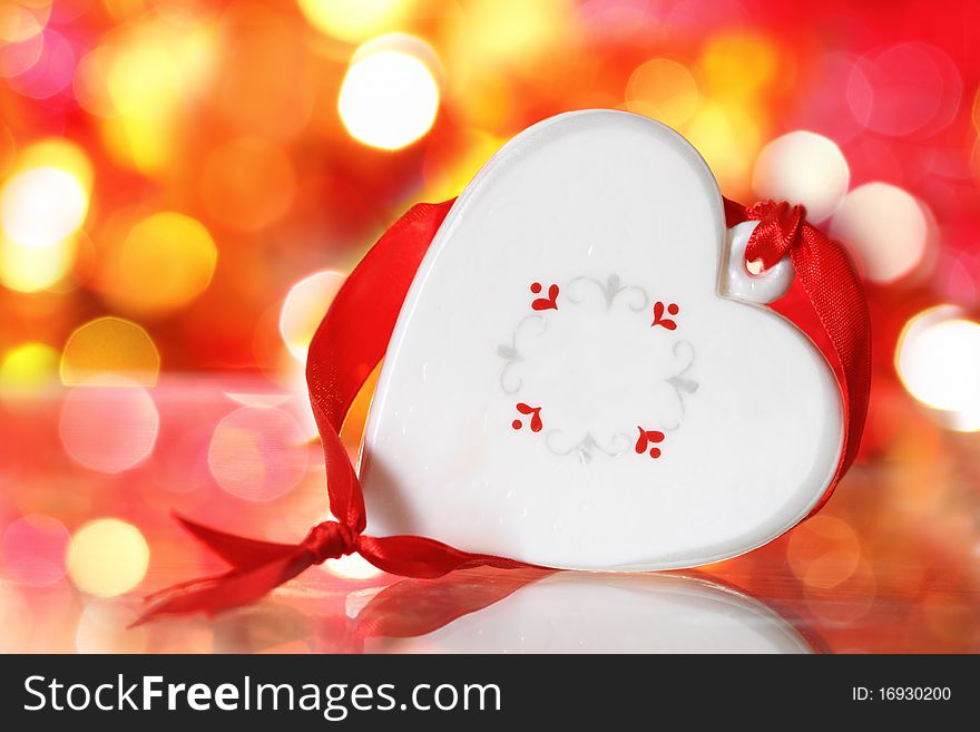 Christmas white heart with red ribbon against blurred background