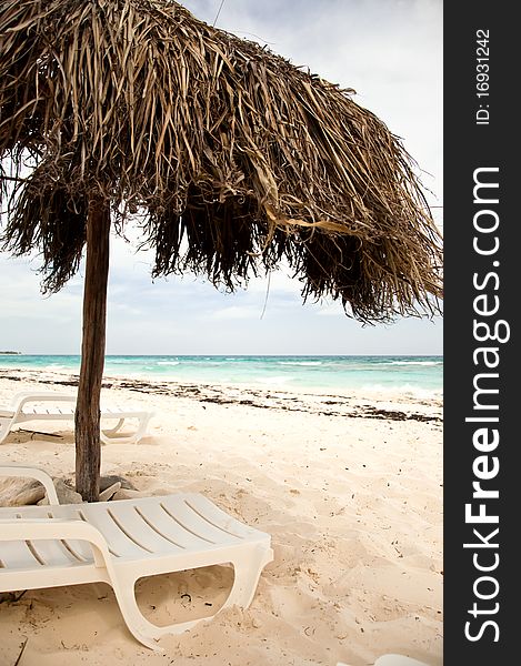 Empty beach with umbrella and two chairs