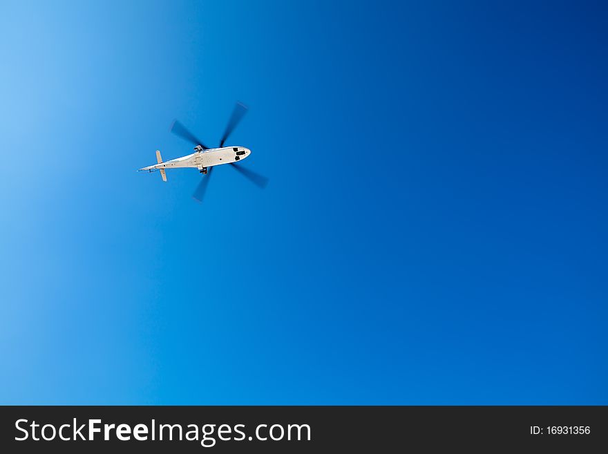 A helicopter from below against a blue sky. A helicopter from below against a blue sky