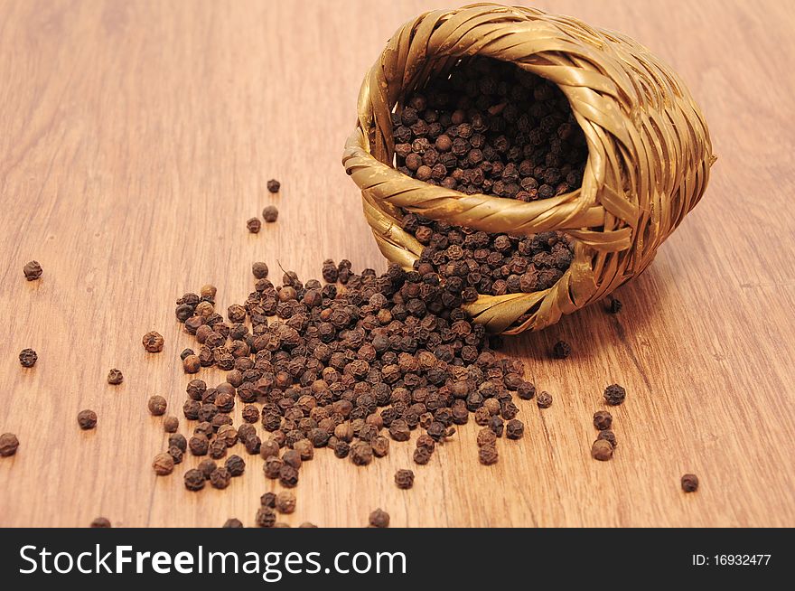 Peppercorns spilled on the table from woven baskets. Peppercorns spilled on the table from woven baskets