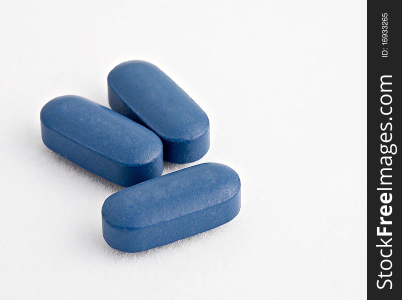 Macro shot of Three blue tablets on white. Macro shot of Three blue tablets on white