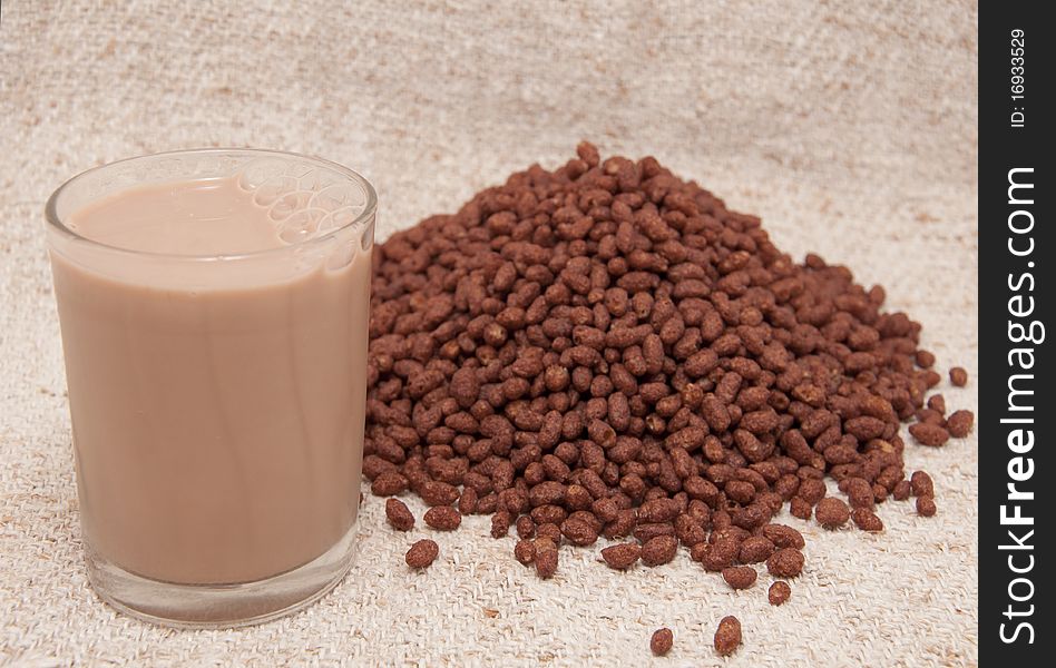 Beaker chocolate milk and cocoa rice crispies on the cloths of linen