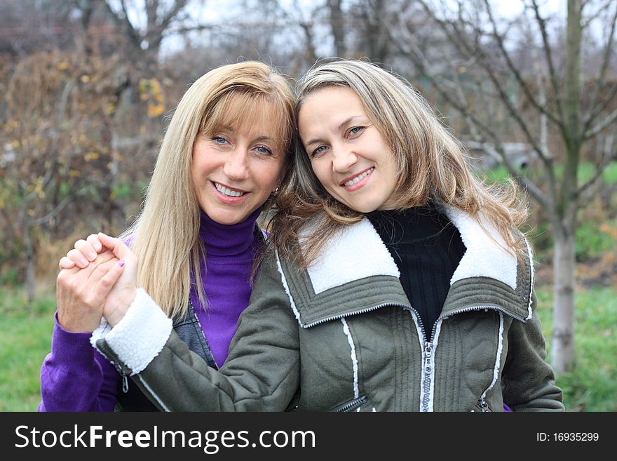 Two women outdoors embracing and smiling. Two women outdoors embracing and smiling