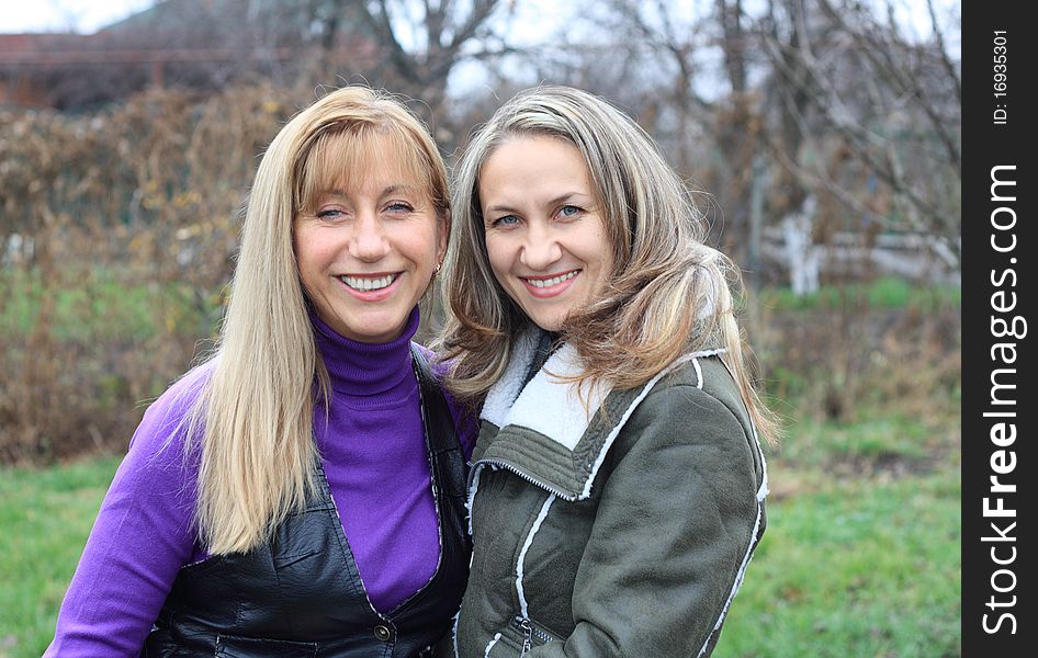 Two women outdoors embracing and smiling. Two women outdoors embracing and smiling