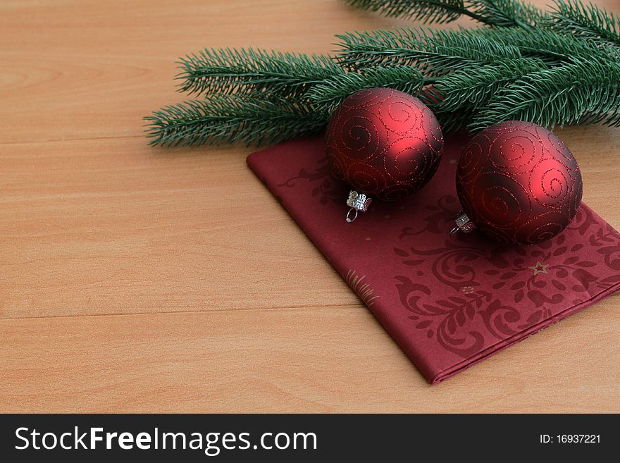 Two red Christmas balls in front of a pine branch