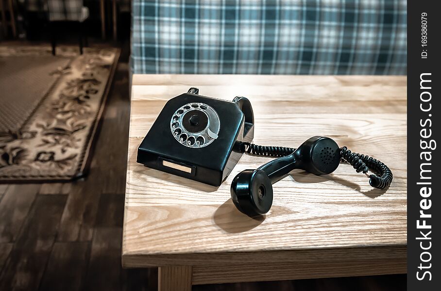 Old vintage black phone with wire on the wooden table