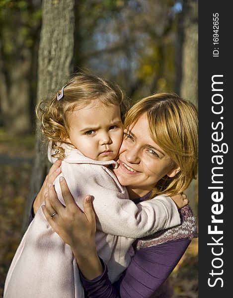 Portrait with little girl in mother's arms in the park. Portrait with little girl in mother's arms in the park