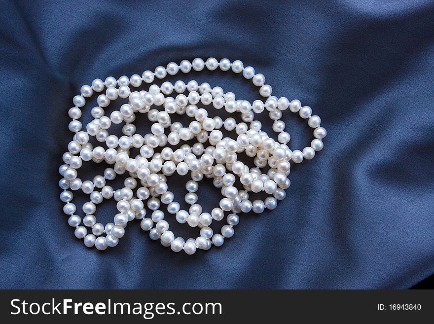 Beatiful white pearls necklace on blue satin