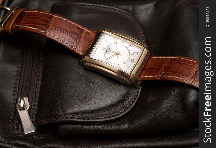 Gold watch lying on a leather purse