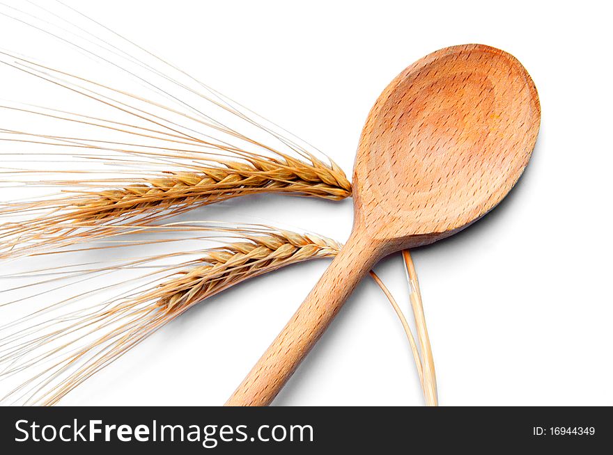Ear of wheat and wooden spoon on white background