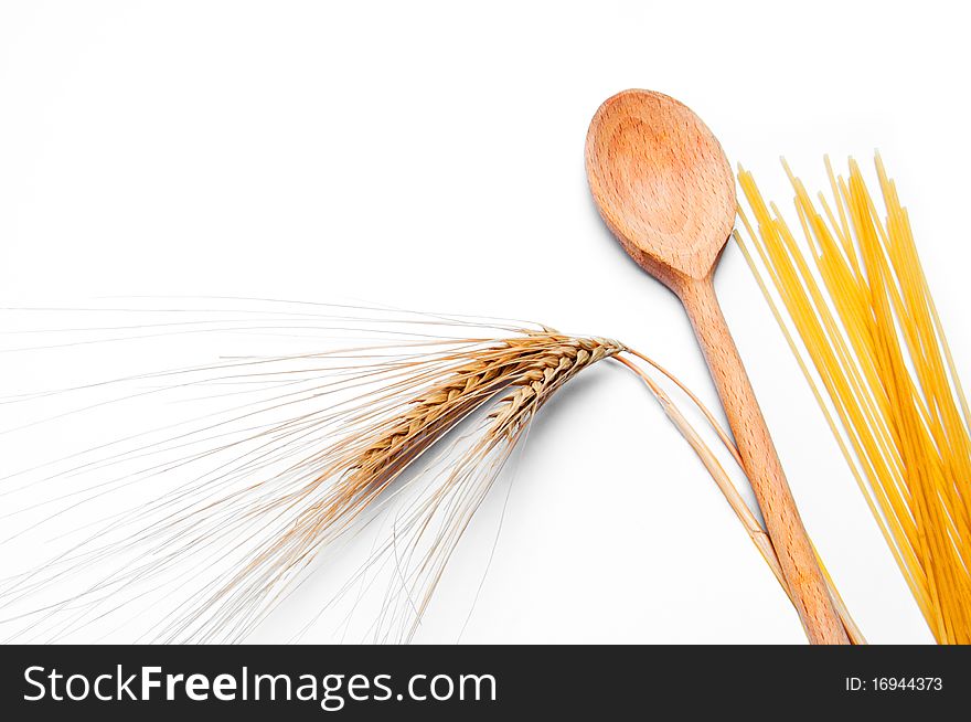 Ear of wheat, pasta and wooden spoon on white background