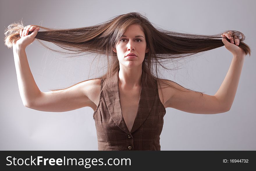 A striking portrait of a gorgeous young woman with long brown hair, holding it straight out to the sides as she stares intensely into the camera. A striking portrait of a gorgeous young woman with long brown hair, holding it straight out to the sides as she stares intensely into the camera.