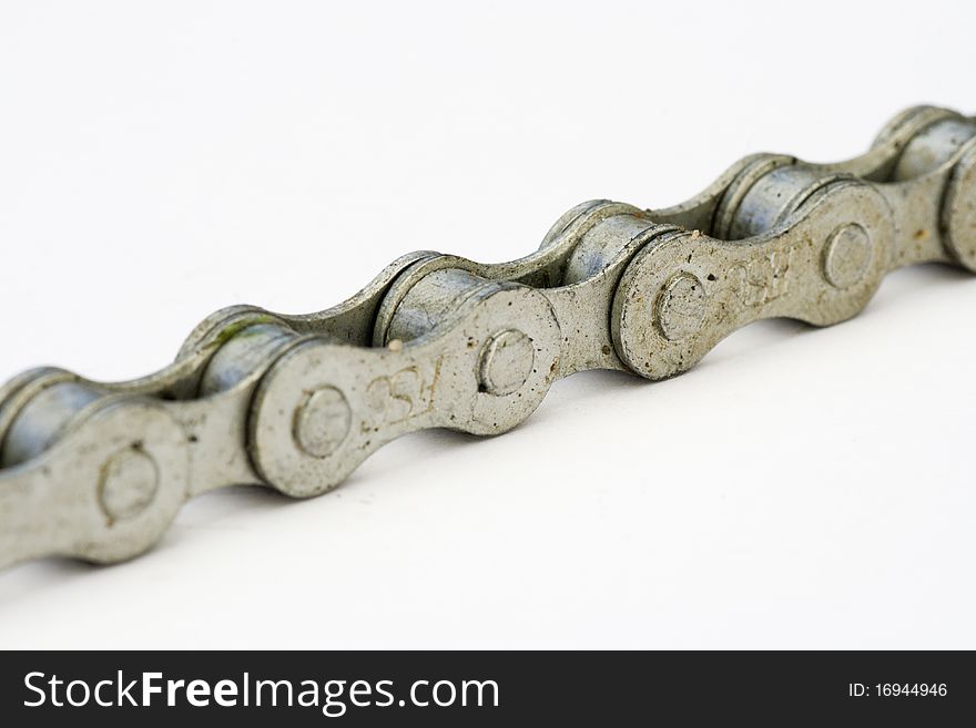 Close up of a dirty bicycle chain lying on a white surface