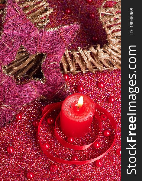Red burning candle with christmas decorations placed on beads