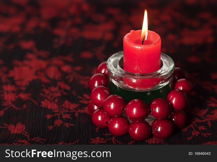 Birning candle with red beads placed on textile