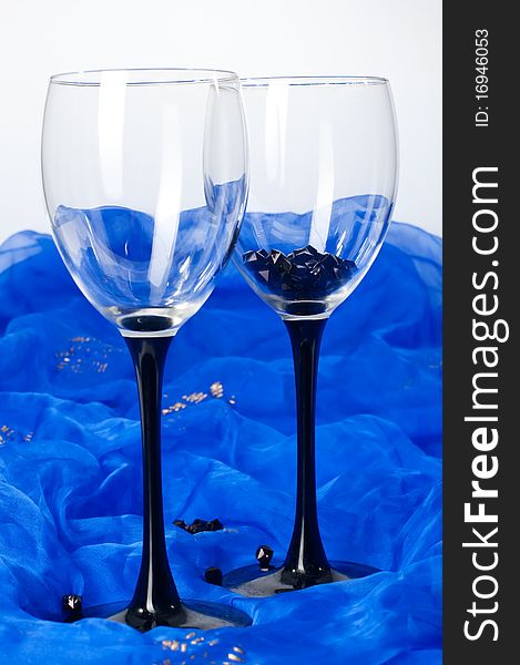 Two glasses with beads placed on blue textile. Two glasses with beads placed on blue textile
